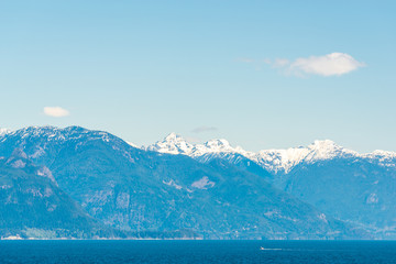 View over inlet, ocean and island with boat and mountains in beautiful British Columbia. Canada.