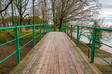 Pedestrian wooden bridge near the river in the warm winter.