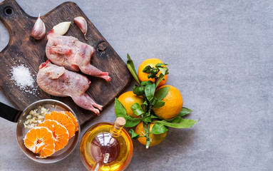 raw quails on the cutting board ready to be baked with tangerines