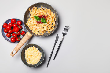 Frying pan with tasty pasta, tomato sauce and cheese on white background