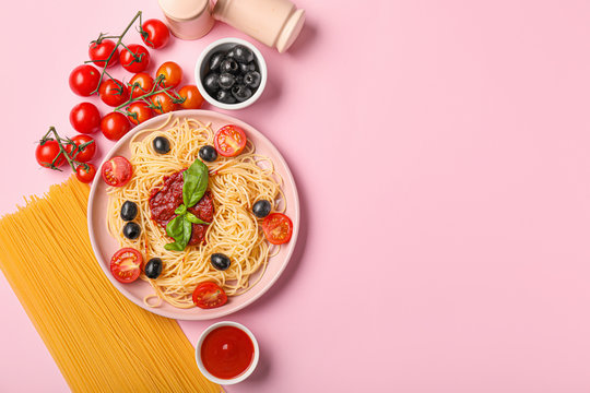 Plate with tasty pasta, olives and tomato sauce on color background