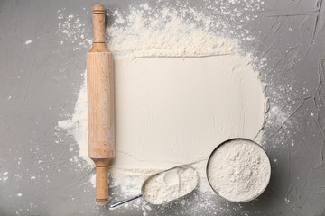 Flour with rolling pin on grey background