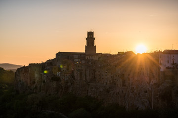 Obraz premium Panoramic view of small vilage in Italy with red brick houses and towers and nature at golden hour with beautiful sky clouds in Grosse province in Tuscany Italy during sunset and warm light