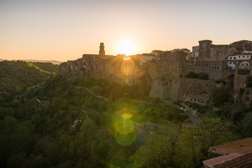 Fototapeta premium Panoramic view of small vilage in Italy with red brick houses and towers and nature at golden hour with beautiful sky clouds in Grosse province in Tuscany Italy during sunset and warm light