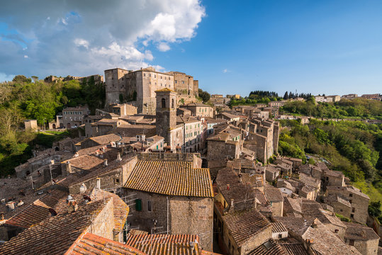 Panoramic view of small vilage in Italy with red brick houses and towers and nature in Sovana Sorano with beautiful sky with clouds in Lazio region Viterbo province in Italy