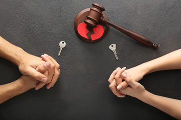Hands of couple with keys and judge's gavel on dark background. Concept of divorce