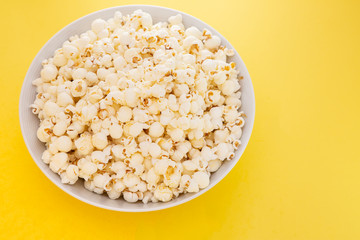 Fototapeta na wymiar Butter popcorn in a red popcorn cup, snack in the house or cinema on a yellow background