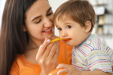 Mother feeding her little son in kitchen