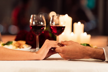 Closeup Of Couple Holding Hands On Served Restaurant Table, Cropped