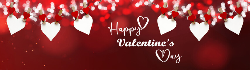 Happy Valentine's Day background banner panorama - White heart hang on wooden clothes pegs with wooden heart and bokeh lights on a string isolated on red texture with bokeh lights, with space for text