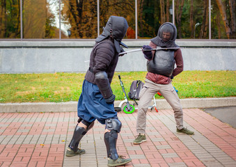 Two armed men lead a sword fight, a medieval fight, at a fun medieval tournament.