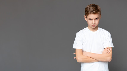 Offended teen boy standing with folded arms, panorama