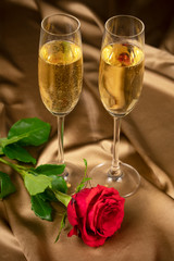 red roses and two glasses of champagne on a background of gold brocade in honor of Valentine's day wedding day, anniversary