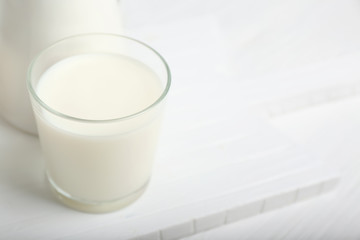 Glass of tasty milk on white table
