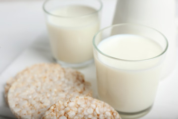 Glasses of tasty milk with crispbread on table