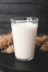 Glass of tasty milk on dark table