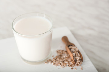 Glass of tasty oat milk on white table