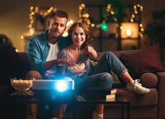 Family couple watching television projector at home on sofa