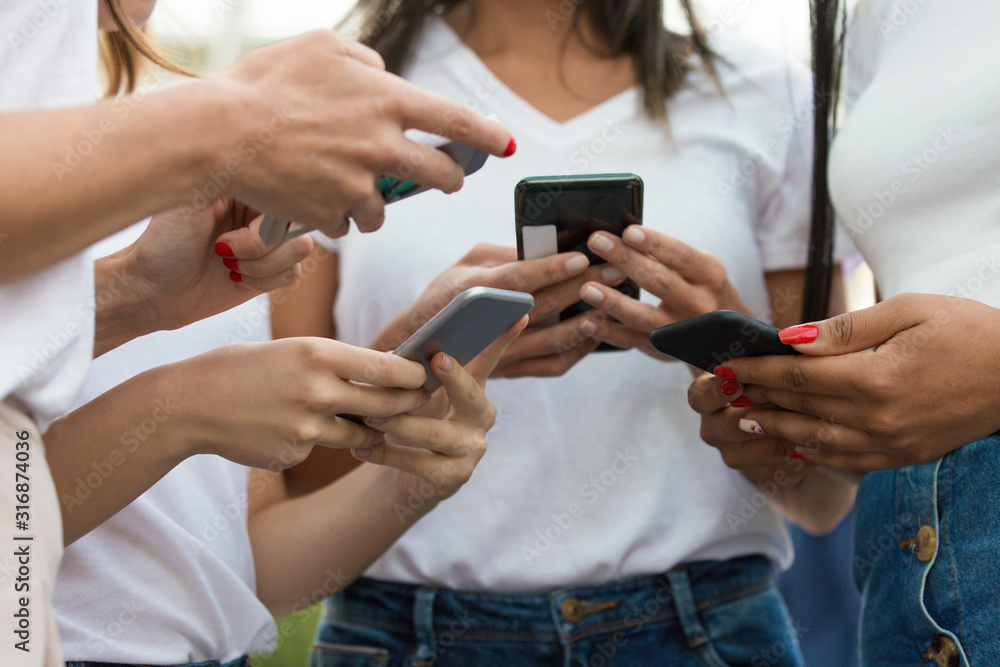 Wall mural cropped shot of young women using modern phones. closeup shot of female hands typing on smartphones.