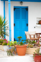 Greek blue door with whitewashed stucco walls framed by Mediterranean potted plants