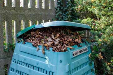 Full Outside plastic  compost container with leaves and branches. Text on polish 
