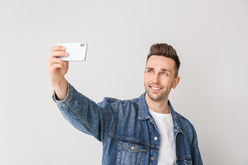 Handsome man taking selfie on light background