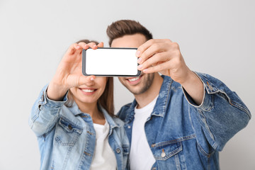 Young couple taking selfie on light background