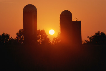 Silhouetted grain elevator against sunrise