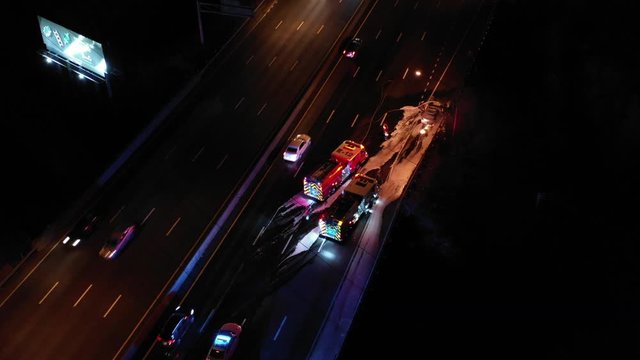 Fire rescue extinguishing car on fire highway at night drone shot