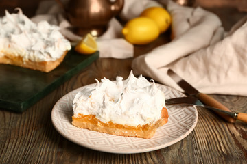 Plate with piece of tasty lemon pie on table