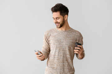 Happy young man with mobile phone on grey background