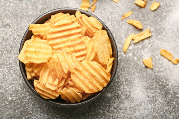 Plate with tasty potato chips on table
