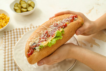 Woman with tasty hot dog at table
