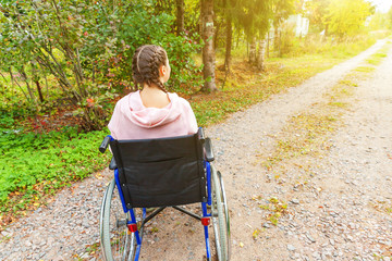 Young happy handicap woman in wheelchair on road in hospital park waiting for patient services....