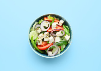 Bowl of tasty Greek salad on color background