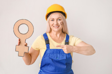 Female worker with symbol of woman on light background. Concept of feminism