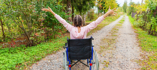 Young happy handicap woman in wheelchair on road in hospital park enjoying freedom. Paralyzed girl...