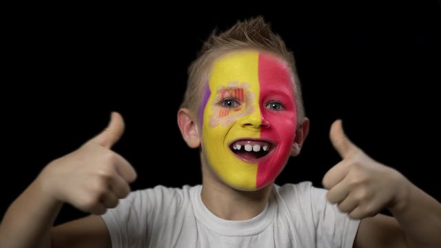 Happy boy rejoices victory of his favorite team of Andorra. A child with a face painted in national colors. Portrait of a happy young fan. Joyful emotions and gestures. Victory. Triumph.