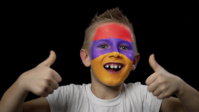 Happy boy rejoices victory of his favorite team of Armenia. A child with a face painted in national colors. Portrait of a happy young fan. Joyful emotions and gestures. Victory. Triumph.