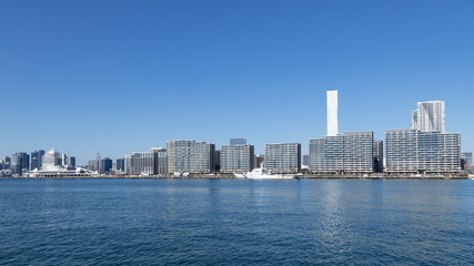 Fototapeta na wymiar 青空を背景に豊洲ふ頭から見た東京湾岸のビル群と選手村