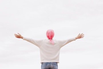 Stock photo of a woman with a pink handkerchief on her head. She has cancer