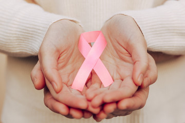 Stock photo of a pink ribbon on women's hands