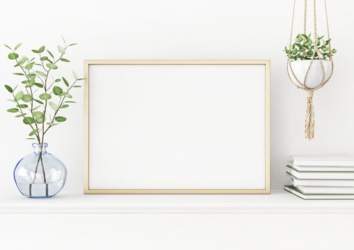 Interior poster mockup with horizontal gold metal frame on the table with plants in blue vase and hanging macrame pot on empty white wall background. A4, A3 size format. 3D rendering, illustration.