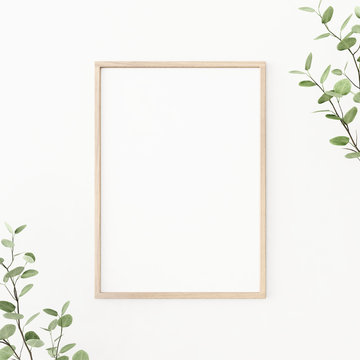 Interior poster mockup with vertical wooden frame on empty white wall, decorated with plant branches with green leaves. A4, A3 size format. 3D rendering, illustration.