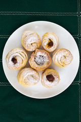 Cruffins on a white plate on a green background.