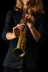 soprano saxophone in hands on a black background