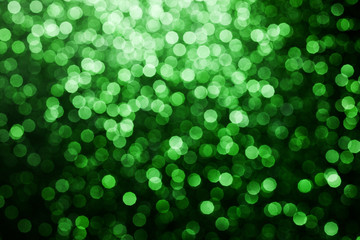 Obraz premium Party festive happy glitter texture. Green bokeh shiny background. Abstract vibrant color glowing white spots texture for graphic design. Magic colorful backdrop.