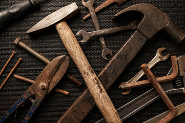 Old tools on dark metal panel.