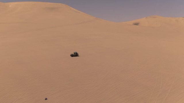 Dune buggy. Sandy desert oasis lake. DRONE. Adventure Dune Buggy. Speed. Tourism shot in Huacachina, Peru. Epic, Fast. Water in middle of hot sand desert. Romantic, holiday, honeymoon, scenic shot.