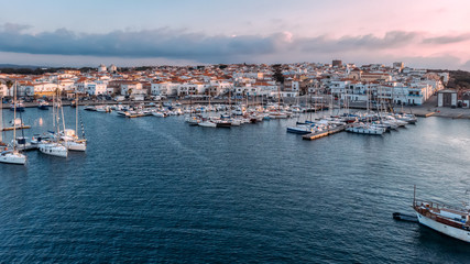Fototapeta premium Widescreen aerial view of lagoon with moored boats and yachts. Blue color of sea. Drone photo. Beauty cloudy sunset on Sardinia, Mediterranean island. Vacation and tourism concept.